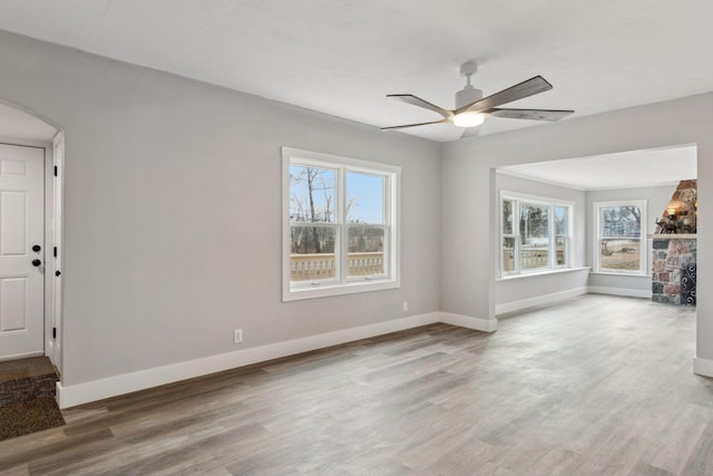 2979 Centerville Rd, Little Canada, MN 55117 - unfurnished living room with baseboards, arched walkways, a ceiling fan, and wood finished floors