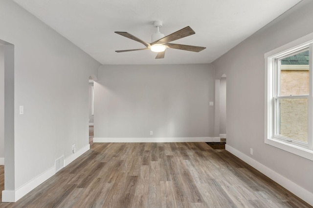 2979 Centerville Rd, Little Canada, MN 55117 - empty room featuring a ceiling fan, visible vents, arched walkways, wood finished floors, and baseboards