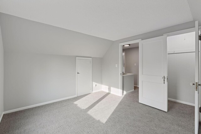 2979 Centerville Rd, Little Canada, MN 55117 - unfurnished bedroom with baseboards, a closet, lofted ceiling, a spacious closet, and carpet
