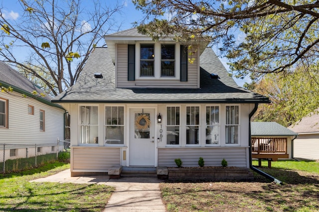 bungalow-style home with a shingled roof, fence, and entry steps