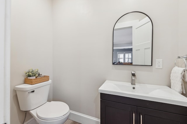 bathroom featuring baseboards, vanity, toilet, and wood finished floors