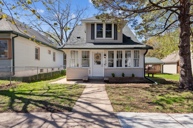 view of front facade featuring roof with shingles, fence, and a front yard