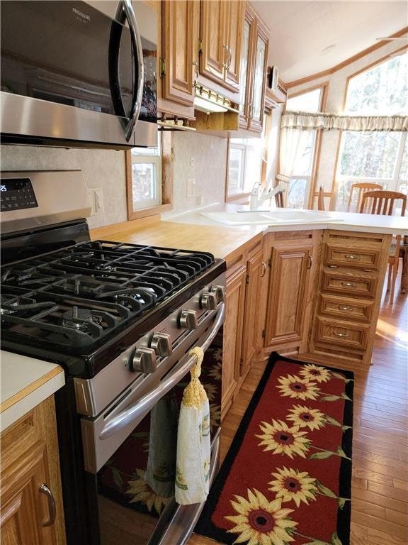 A6 Pathfinder Vlg, Hinckley, MN 55037 - kitchen featuring appliances with stainless steel finishes, light countertops, dark wood-style flooring, a peninsula, and brown cabinetry