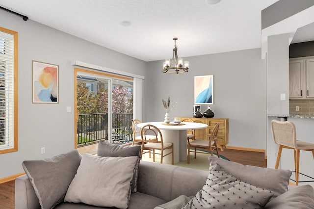 dining space with a chandelier, baseboards, and wood finished floors