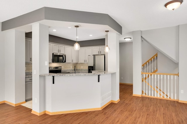 kitchen with appliances with stainless steel finishes, light wood-style flooring, baseboards, backsplash, and light stone countertops