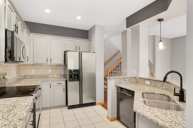 kitchen featuring appliances with stainless steel finishes, a sink, light stone countertops, hanging light fixtures, and recessed lighting