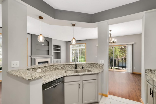 kitchen with dishwasher, a sink, and light stone countertops