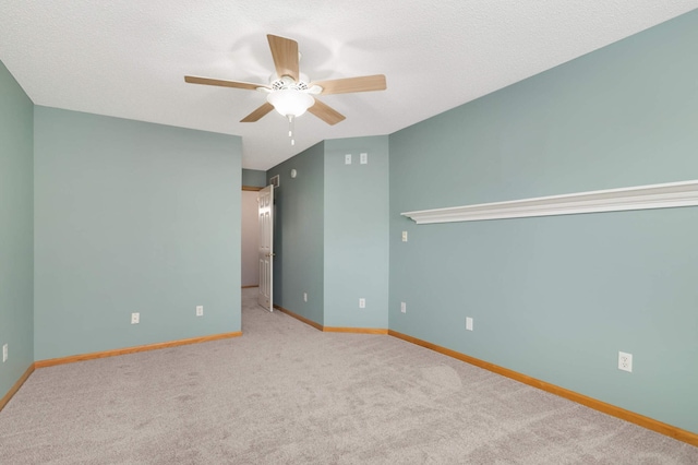 carpeted spare room with ceiling fan, baseboards, and a textured ceiling