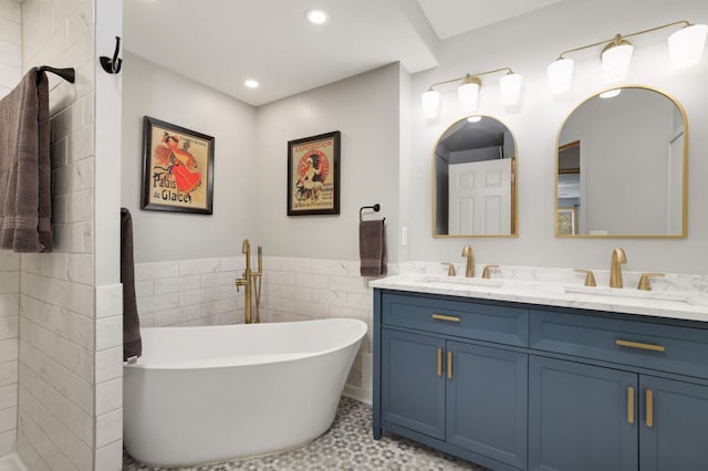 bathroom featuring tile walls, double vanity, a freestanding tub, and recessed lighting