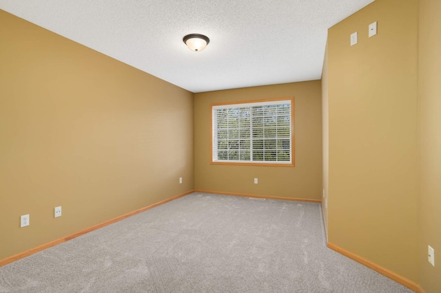 carpeted spare room with baseboards and a textured ceiling