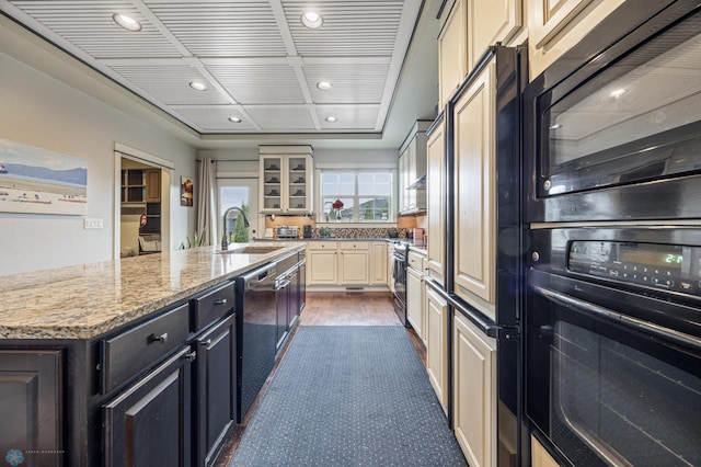 6028 Silverleaf Dr S, Fargo, ND 58104 - kitchen featuring a sink, black appliances, glass insert cabinets, recessed lighting, and an island with sink