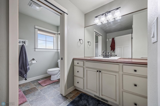 6028 Silverleaf Dr S, Fargo, ND 58104 - bathroom with visible vents, stone tile floors, baseboards, and toilet
