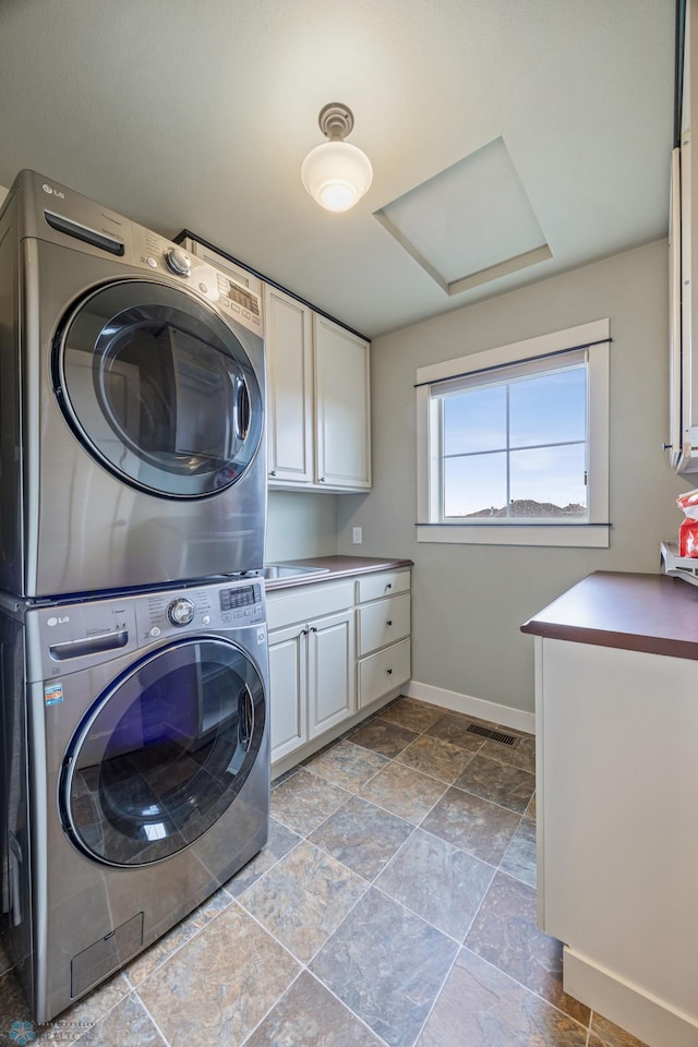 6028 Silverleaf Dr S, Fargo, ND 58104 - laundry area featuring visible vents, stacked washer / dryer, baseboards, attic access, and cabinet space