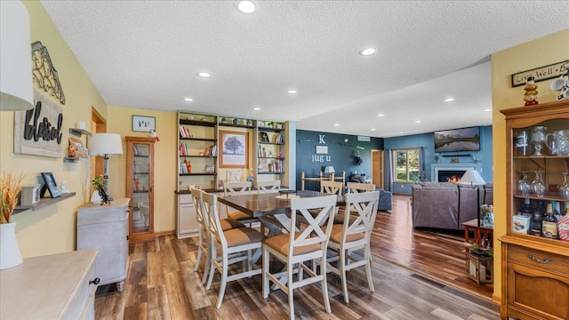 21151 150th St, Sauk Centre, MN 56378 - dining space with a textured ceiling, wood finished floors, recessed lighting, and a warm lit fireplace