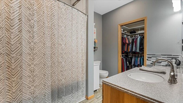 21151 150th St, Sauk Centre, MN 56378 - full bathroom with toilet, vanity, a shower with curtain, a walk in closet, and wood finished floors