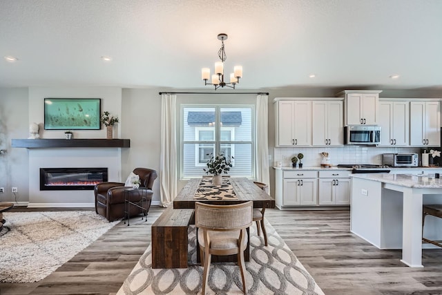 13665 Marsh View Trl, Rogers, MN 55374 - kitchen featuring tasteful backsplash, light wood-type flooring, a toaster, stainless steel microwave, and a notable chandelier