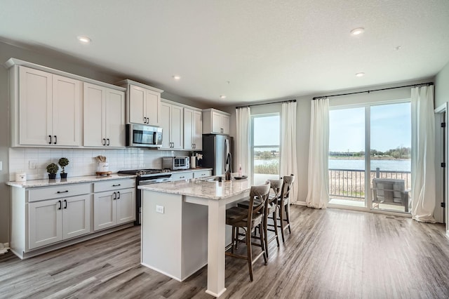 13665 Marsh View Trl, Rogers, MN 55374 - kitchen featuring a sink, a kitchen island with sink, stainless steel appliances, light wood-type flooring, and backsplash