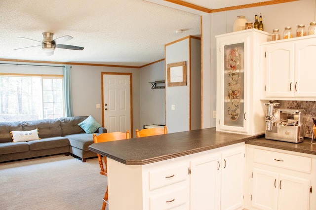 4684 Lower Ten Mile Lake Rd NW, Hackensack, MN 56452 - kitchen featuring dark countertops, ornamental molding, a ceiling fan, a peninsula, and white cabinets
