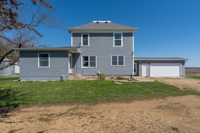 rear view of property with a garage, dirt driveway, and a yard