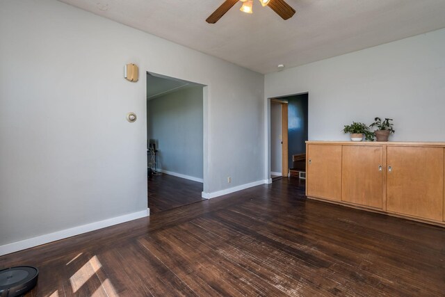 spare room with a ceiling fan, baseboards, and dark wood-style floors