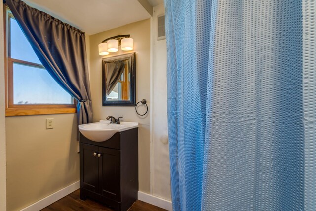 full bath with baseboards, vanity, and wood finished floors