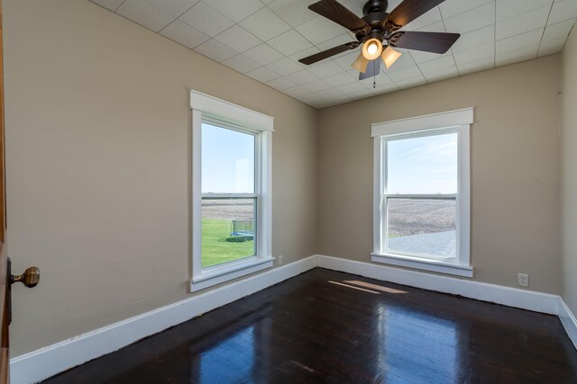 unfurnished room with baseboards, dark wood-style flooring, and a wealth of natural light