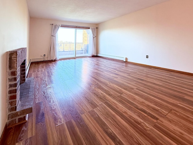 unfurnished living room with baseboards, a baseboard heating unit, and wood finished floors
