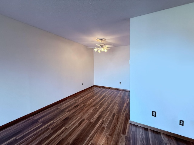 spare room featuring baseboards, ceiling fan, and dark wood-style flooring