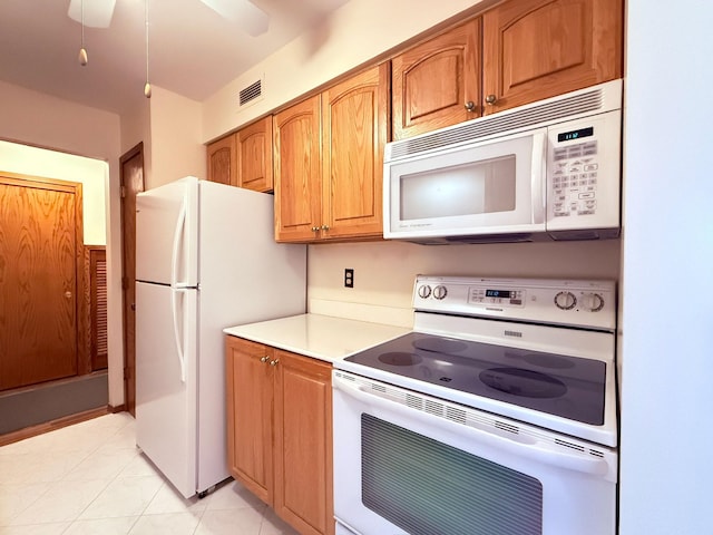 kitchen with brown cabinets, white appliances, light countertops, light tile patterned floors, and visible vents