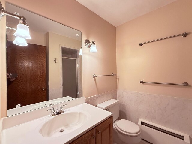 full bathroom with vanity, toilet, tile walls, baseboard heating, and a stall shower