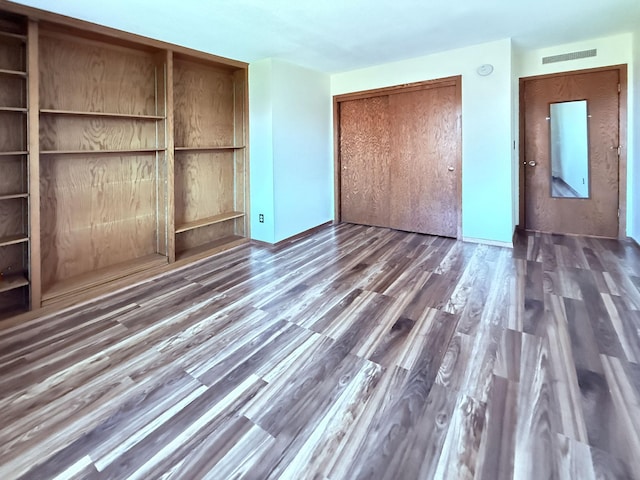 unfurnished bedroom with visible vents, wood finished floors, and a closet