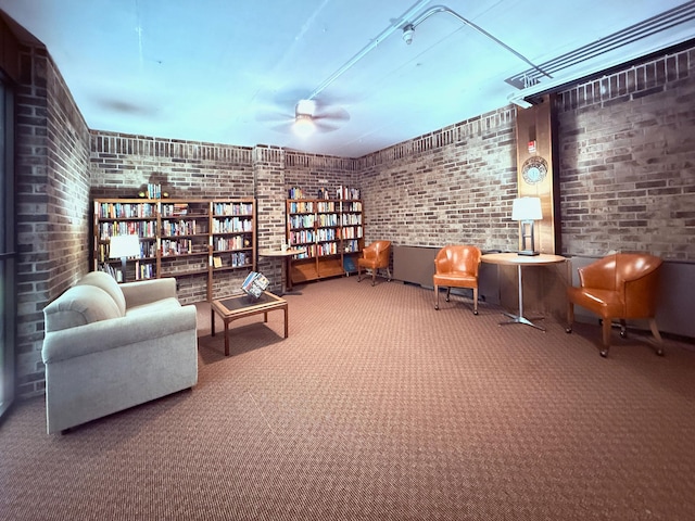 sitting room featuring brick wall, ceiling fan, and carpet