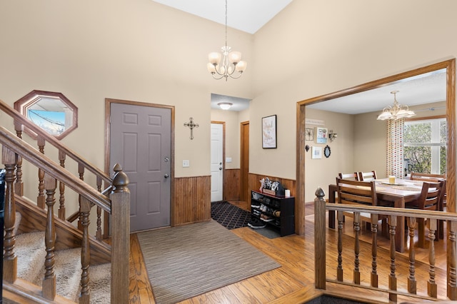 foyer with wooden walls, wainscoting, wood finished floors, and a notable chandelier