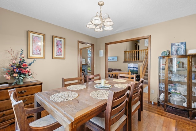 dining space featuring an inviting chandelier, stairway, and light wood-style flooring