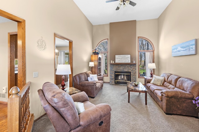 living area with ceiling fan, a high ceiling, carpet, and a fireplace