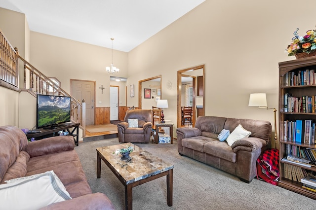 living room featuring carpet, stairs, a chandelier, and a towering ceiling