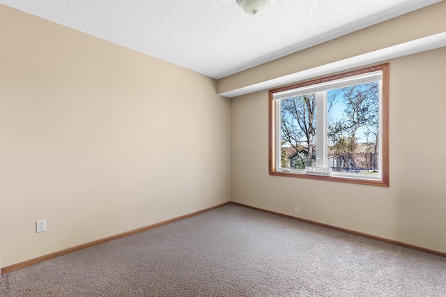 carpeted spare room with baseboards and a textured ceiling