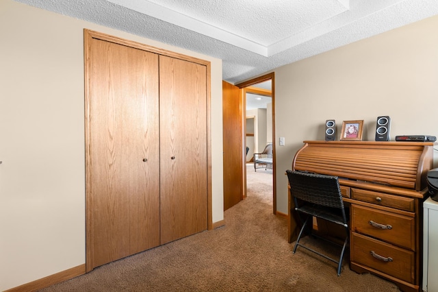 carpeted office space with a textured ceiling and baseboards
