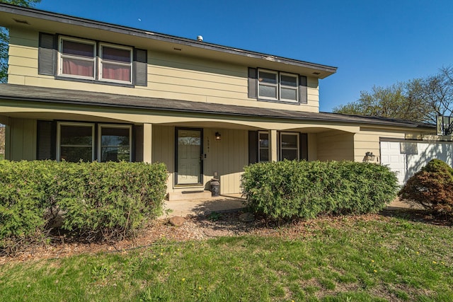 traditional-style house featuring covered porch, an attached garage, and a front lawn
