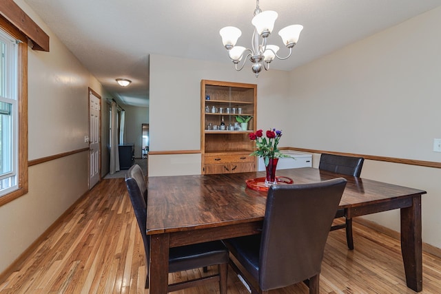 dining area featuring light wood-style flooring and a notable chandelier