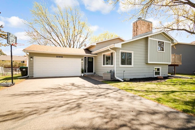 split level home with driveway, a chimney, a front yard, and a garage