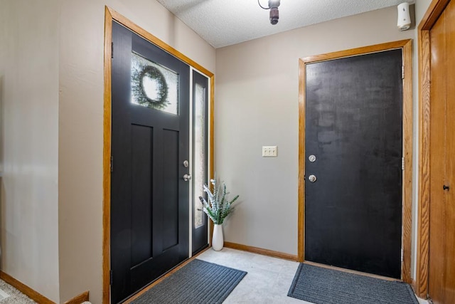 foyer entrance with a textured ceiling and baseboards