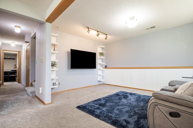carpeted living area featuring stairway, baseboards, a textured ceiling, and visible vents