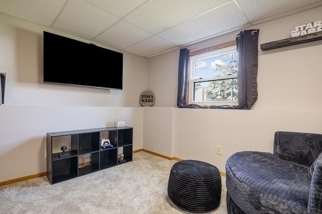 living area with baseboards, carpet flooring, and a paneled ceiling