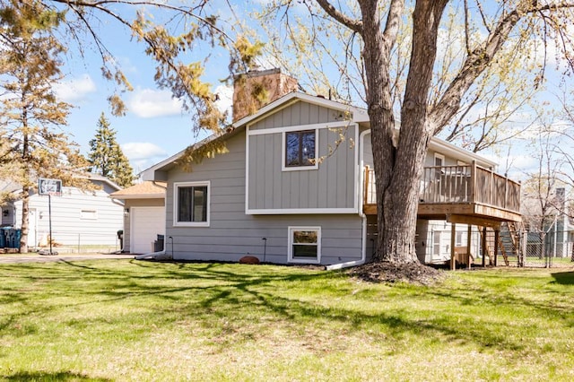 back of house with a yard, a deck, a chimney, and a garage