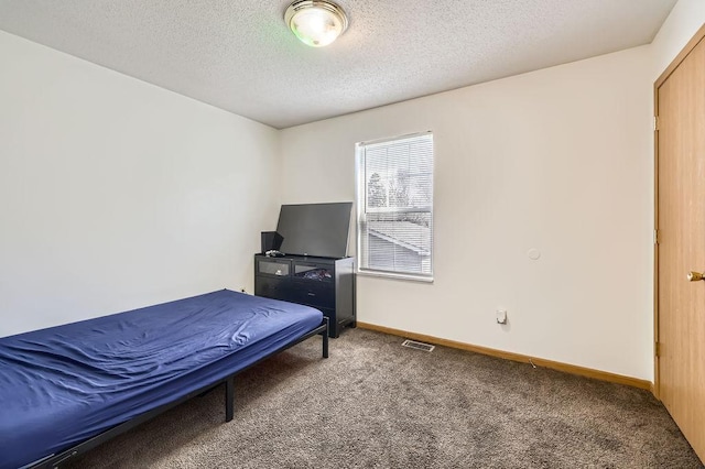 carpeted bedroom featuring baseboards, a textured ceiling, and visible vents