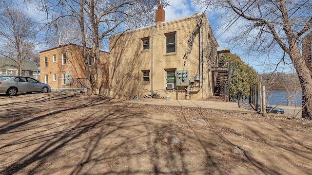 back of house with a chimney and brick siding