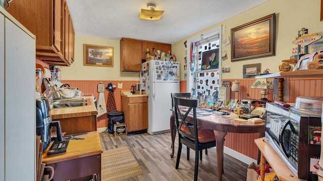 dining room with a wainscoted wall and light wood-style flooring
