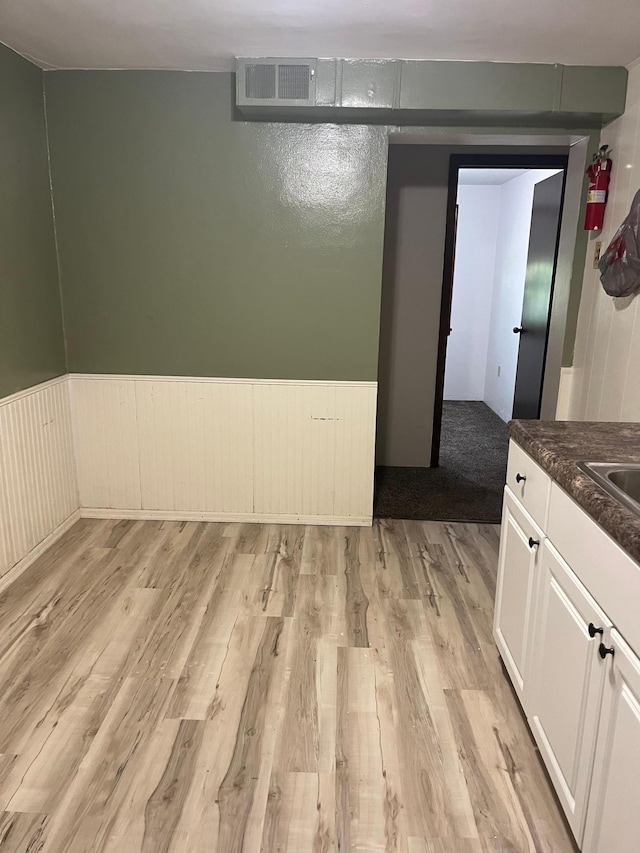 629 5th Ave N, Saint Cloud, MN 56303 - unfurnished dining area with light wood-type flooring and a wainscoted wall