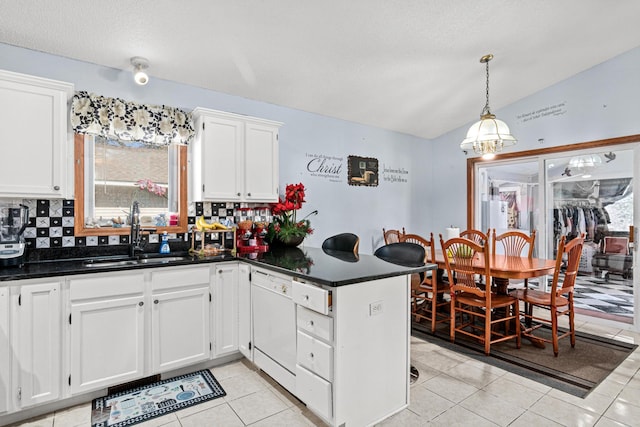 kitchen featuring backsplash, dishwasher, a sink, white cabinets, and a peninsula